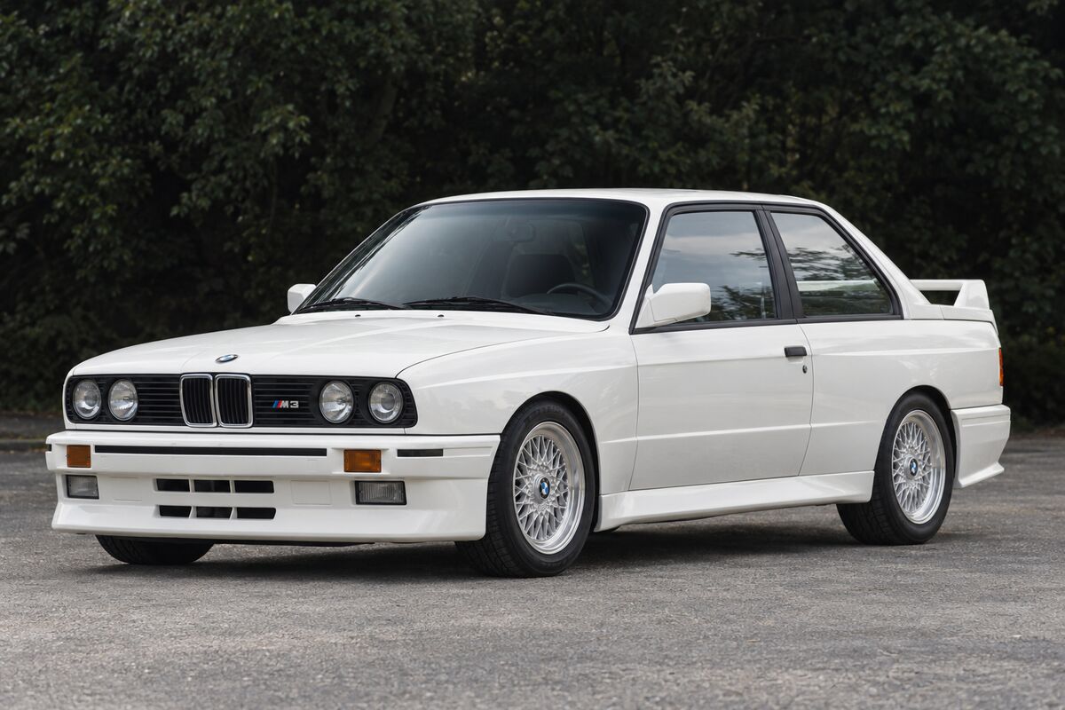 A white first-generation BMW M3 from the front left.